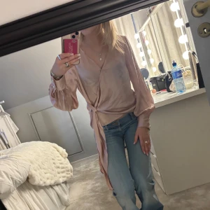 Ljusrosa omlottblus i satin - Fin topp, dock sitter knappen där fram löst