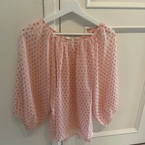 Rosa prickig blus från Part Two Copenhagen - Säljer en luftig blus från Part Two i ljusrosa med rosa prickar. Blusen har trekvartsärmar och en lös passform med rund halsringning. Perfekt för vår och sommar!