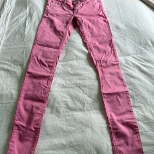 Jeans - Säljer ett par rosa jeans från Replay. Byxorna har klassisk femficksdesign, dragkedja och knapp framtill samt smal passform. Perfekta för dig som vill sticka ut med färg i vardagen.