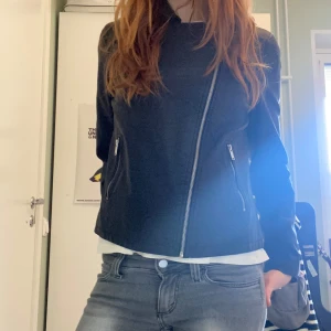 Svart skinnjacka från Only You - Säljer en svart skinnjacka från Only You med sned dragkedja och två fickor med dragkedjor. Jackan har klassisk krage och stilren design, perfekt för en cool look. På sista bilden syns ett litet hål men som ej syns på