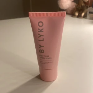 BY LYKO Grip That Base Primer - En rosa tub med BY LYKO Grip That Base Primer. Primern jämnar ut huden och ger en slät bas för smink. Tuben är i plast och har ett stilrent, modernt utseende med text i silver. Perfekt för att förbereda huden innan foundation. I nytt skick då den bara är använd 2-3 gånger!