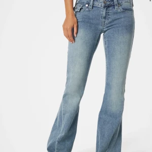 Blå bootcut jeans från True Religion - Snygga blå bootcut jeans från True Religion med klassiska sömmar och detaljerade bakfickor med lock och knapp. Jeansen har låg midja och är tillverkade i denim med lätt tvättad look. Jag har använt jeansen max 5 gånger då dom är förstora för mig  💕
