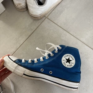 Blå Converse All Star höga sneakers - Säljer ett par klassiska blå höga Converse All Star sneakers med vit sula och vita snören. Knappt använda 