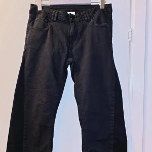 Svarta jeansbyxor - Svarta jeansbyxor med klassisk femficksdesign och raka ben. Byxorna har knapp och dragkedja framtill samt bälteshällor i midjan. Perfekta för en stilren och enkel look. Byxornar är baggy och passar perfekt för varje dags användning! 