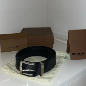 Svart skärp från Burberry - Säljer ett stilrent svart skärp från Burberry i skinn med Burberry-loggan är ingraverad. Skärpet har klassisk design och levereras med originalpåse och förpackning.
