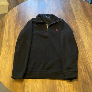 Ralph lauren quarter zip - Säljer en stilren svart quarter zip från Ralph Lauren med ribbad krage. Tröjan är i bra skick och perfekt nu till sommaren. Tveka inte på att lägga bud eller fråga frågor🤝