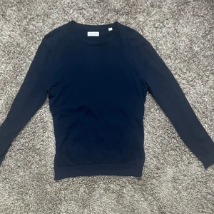 Stickad sweatshirt från Jack & Jones - Säljer en stilren mörkblå tröja från Jack & Jones i storlek XS. Tröjan har lång ärm och rund halsringning, perfekt för lager-på-lager eller som den är. Enkel och klassisk design som passar till det mesta.