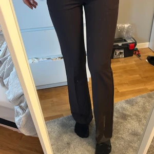 Bruna kostymbyxor med bootcut- vera lowwaist - Säljer ett par bruna kostymbyxor från bikbok . Byxorna har bootcut-modell och normal passform, med klassisk midja och diskreta fickor bak. Perfekta för en stilren look.