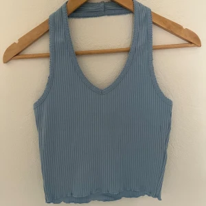 Ljusblå ribbad linnetopp från Bik Bok - Säljer en ljusblå ribbad linnetopp från Bik Bok. Toppen har v-ringning och är ärmlös med croppad passform. Perfekt för varma dagar och enkel att matcha med jeans eller kjol.