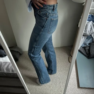 Blå raka jeansbyxor från & otier stories - Säljer ett par klassiska blå jeansbyxor med raka ben och medelhög midja. Perfekta för en stilren och enkel look.🩵