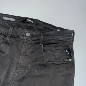 Svarta Replay Hyperflex jeans - Säljer ett par svarta Replay Hyperflex jeans med klassisk femficksdesign och normal passform. Jeansen har dragkedja och knapp i gylfen samt diskret Replay-logga på fickan. Perfekta för dig som gillar stretchiga och bekväma jeans.