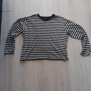Randig långärmad tröja - Säljer en svartvit randig tröja med långa ärmar. Perfekt för en avslappnad stil. Tröjan har en klassisk design med rund halsringning.