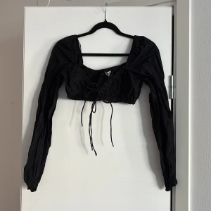 Svart långärmad topp från HM - Snygg svart långärmad topp från HM med knytning framtill. Använd endast några gånger är i snyggt skick 
