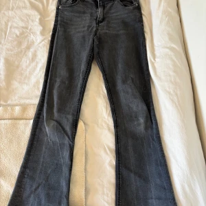 Grå bootcut jeans från Gina Tricot - Snygga grå bootcut jeans från Gina Tricot. De har en klassisk femficksdesign och en knappgylf. Perfekta för en stilren look.