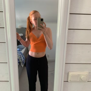 Orange ribbad croppad linnetopp - Säljer en orange croppad linnetopp med omlott och v-ringning. Toppen har breda axelband med vågig kant och är ribbad i materialet. Perfekt för varma dagar eller som ett färgglatt inslag i garderoben. Oanvänd. 