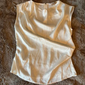 Vit ärmlös topp från H&M - Säljer en stilren vit ärmlös topp från H&M. Toppen har dragkedja i ryggen. Perfekt att matcha med både jeans och kjol✨Använd 1 gång och inga defekter🫶🏼
