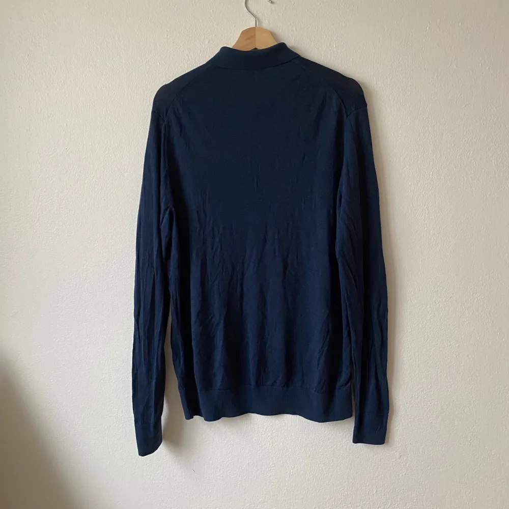 Säljer en stilren mörkblå pikétröja från Uniqlo i storlek L. Tröjan har lång ärm, klassisk krage och knäppning framtill. Perfekt för en clean och enkel look. Materialet känns mjukt och lätt. Artnr: Q215. Neuletakit & Villapaidat.