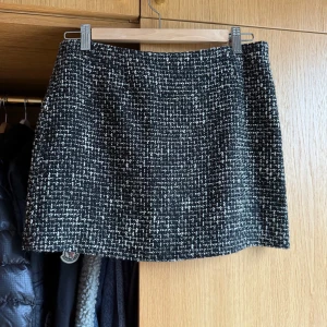 Svartvit tweedkjol - Säljer en svartvit kortkjol i tweed-look med klassiskt rutigt mönster. Kjolen har rak passform och är perfekt för dig som gillar en stilren och trendig vibe. Passar till många olika outfits och är enkel att matcha.