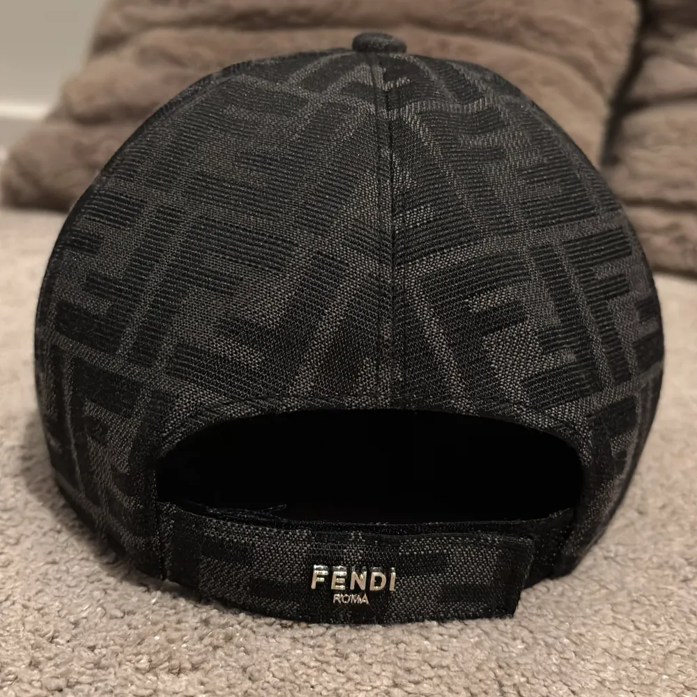 Säljer en svart keps från Fendi med deras ikoniska FF-monogram i hela tyget. Kepsen har böjd skärm med svart kant och justerbar rem baktill med Fendi-logga. Snygg och stilren accessoar för dig som gillar designerplagg. Nyskick fast använd ett antal gånger.. Asusteet.