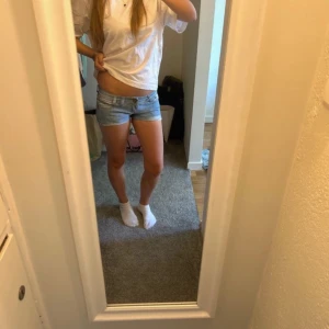 Ljusblå jeansshorts - Säljer ett par ljusblå jeansshorts med en klassisk design. De är perfekta för sommardagar och har en bekväm passform. Shortsen är lågmidjade och har en snygg, enkel stil som passar till det mesta. Perfekta för en avslappnad look!