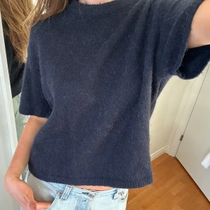 Mörkblå stickad tröja - Säljer en mysig mörkblå stickad tröja med korta ärmar. Perfekt för en avslappnad stil. Tröjan har en enkel design och är lätt att matcha med olika outfits. Passar superbra nu till vår och sommar! Fint skick🤍