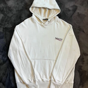 Balenciaga hoodie - Vit hoodie från Balenciaga med logga tryckt på bröstet och stor logga på ryggen. Storlek XL, men passar med oversized L, skick 7/10 använd och nån fläck men inga defekter förutom att snören saknas. Köpt på secondhand i Köpenhamn så kan ej garantera att den är  äkta. Pris går att diskutera ✅