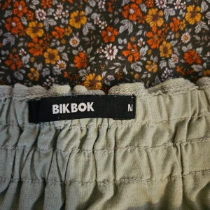 Grön off-shoulder topp från Bik Bok - Säljer en snygg grön off-shoulder topp från Bik Bok. Toppen har en elastisk smockdetalj vid halsen och långa ärmar. Perfekt för en stilren look!