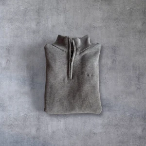 Grå tröja med halv dragkedja från Bondelid - Säljer en stilren grå tröja från Bondelid med halv dragkedja och ribbade muddar. Perfekt för en klassisk look. Tröjan har långa ärmar och en bekväm passform. Mått: L:67 B:49