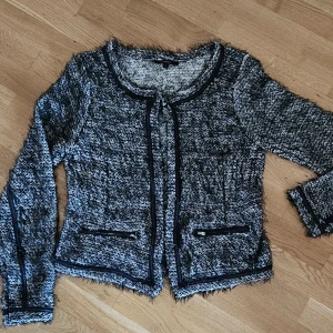 Svart och vit cardigan jacka  - Snygg svart och vit cardigan jacka från Lndex med långärmad design. Jackan har en texturerad yta och svarta kantdetaljer. Perfekt för att lägga till en stilfull touch till din outfit. Liten i storleken. Känns som 40-42. Använd några få gånger och inga skavanker. 50 kr
