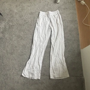 Vita byxor med broderad detalj - Säljer ett par vita byxor med en broderad hjärtdetalj. Byxorna har en loose passform och är tillverkade i ett mjukt material. Perfekta för en avslappnad stil.