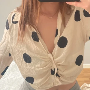 Beige blus med svarta prickar - Säljer en beige blus med stora svarta prickar. Blusen är lite kortare än vanligtvis men super fin till sommaren, som ni ser på bilderna kan man även ha blusen uppknäppt 👌 hör av er ! 