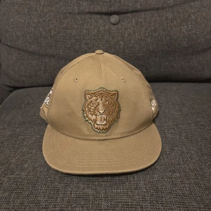 Beige Detroit Tigers keps från New Era - Snygg beige snapback-keps från New Era 9FIFTY med broderad tiger på fronten och Detroit Tigers-logga på sidan. Kepsen har platt skärm och justerbar baksida. Tillverkad i bomull, perfekt för dig som gillar sportig streetstyle.