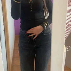 Svart urringad tajt tröja  - Säljer en snygg vintage urringad svart tröja med knappar vid framsidan som ni ser. Tröjan har en tajt passform och formar kroppen mycket väl och fint. Säljer på grund av att det inte kommer till användning och inte är min stil. Tröjan är använd endast fåtal gånger då typ 1-3 gånger och alltför i mycket bra skick.