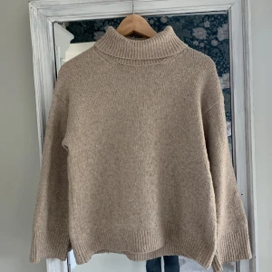 Beige polotröja från Zara - Säljer en beige polotröja från Zara med ribbad krage och muddar. Tröjan är stickad och har en loose passform med långa ärmar. Perfekt för dig som gillar enkel och chill stil under höst och vinter.