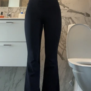 Svarta bootcut byxor med hög midja - Säljer ett par svarta bootcut byxor med hög midja. Byxorna har en tight passform upptill och släpper ut vid bensluten för en snygg siluett. Perfekta att styla med sneakers eller boots. Mjukt och stretchigt material som sitter skönt hela dagen. 