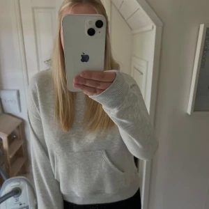 Ljusgrå hoodie med huva - Säljer en ljusgrå hoodie med huva och magficka. Tröjan har långa ärmar och är gjord i mjukt bomullsmaterial, perfekt för chill dagar. Enkel och stilren design som funkar till det mesta. Snygg att matcha med jeans eller leggings. 