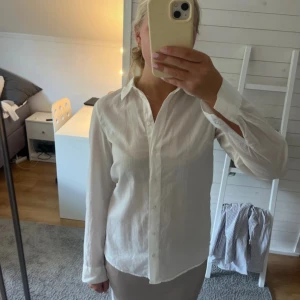 Vit klassisk skjorta i bomull - Snygg vit skjorta med klassisk krage och knappar framtill. Långärmad och tillverkad i lätt bomullstyg som ger en fräsch och stilren look. Perfekt för dig som gillar enkel och tidlös stil.