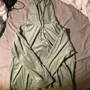 Ljusgrön ribbad hoodie med huva - Säljer en chill ljusgrön tunn hoodie med ribbad struktur och snörning vid huvan. Tröjan har långa ärmar och är gjord i ett mjukt, manchesterliknande material. Perfekt för dig som gillar oversized och comfy vibes.
