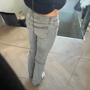 Gråa bootcut jeans med knappar - Säljer ett par ljusgrå jeans med bootcut passform och snygga detaljer med flera knappar i gylfen. Jeansen har klassiska fickor både fram och bak och är tillverkade i mjukt denimtyg. Dem är köpta på ginatricot Young och är i storlek 164, jag är 173 och dom sitter så på. Säljer då dom inte kommer till användning 💞använda 3-4 gånger och är i princip helt nya💞