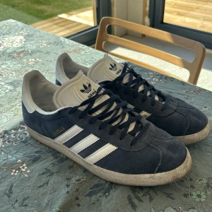 Adidas Gazelle sneakers i mörkblå mocka - Snygga Adidas Gazelle skor i mörkblå mocka, dom är i hyfsat bra skick och inget som är trasigt på dom. Dom är i storlek 44 men passar även 43
