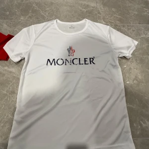 Vit Moncler t-shirt i polyester - Snygg vit t-shirt från Moncler med stor logga framtill i blått och rött!