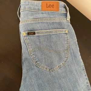 Lee Scarlett Cropped ljusblå jeans - Säljer ett par Lee Scarlett Cropped jeans i ljusblå denim. Modellen är croppad med klassiska femficksdetaljer, dragkedjegylf och snygga kontrastsömmar. Perfekta för dig som gillar en modern och avslappnad look.