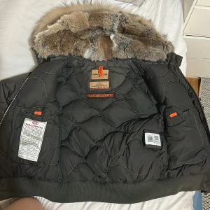 Parajumpers kaki dunjacka med päls XS - Säljer en kaki Parajumpers dunjacka i slim fit med fluffig äkta päls runt huvan. Jackan har flera fickor, dragkedja och coola detaljer som orangea inslag och ribbade muddar. Perfekt för kalla vinterdagar och riktigt snygg streetstil.