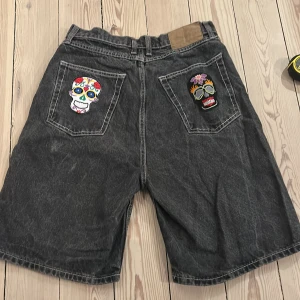 Svarta jeansshorts med döskallar -  svarta jeansshorts/jorts med snygga döskallqr på bakfickorna. Säljer då de inte används🤍🤍Storlek S män. Midjemått ca 37,5 cm, ytterbenslängd  ca 55 cm🤍 priset kan diskuteras 