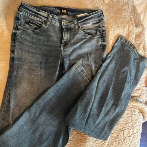 Blå Lee bootcut jeans - Snygga blå jeans från Lee med klassisk bootcut-passform. Jeansen har fem fickor, ljus tvätt och Lee-logga på bakfickan. Nypris runt 1100 kr 