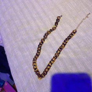 Chunky halsband i guld och brun - Snyggt chunky halsband med grova länkar i guld och brun. Kedjan har en cool, glansig finish och justerbar längd med förlängningskedja. Perfekt för att ge din outfit extra edge och att matcha med andra smycken.