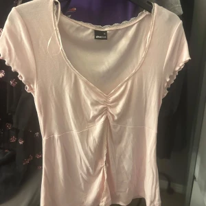 Ljusrosa topp från Gina Tricot - Supersöt ljusrosa topp från Gina Tricot med v-ringning och rynkdetalj framtill. Toppen har öppen mage💕Strl M men den passar även S! 