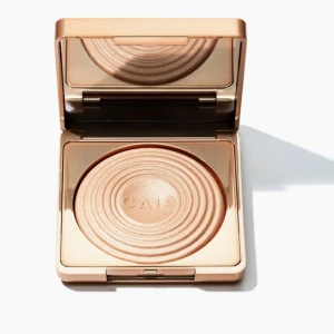 CAIA Highlighter Sydney - Superfin highlighter från CAIA i nyansen Sydney. Kommer i en lyxig, roséguldig dosa med spegel och har en skimrande champagnefärg. Pressad puderform med snyggt cirkelmönster. Perfekt för att ge glow till kindben, näsa och amorbåge. Helt ny oöppnad förpackning😊