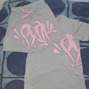 Syna World grå shorts med rosa tryck - Syna World T-shirt + Shorts Set – Storlek M (Grå & Rosa)  Använd endast 4–5 gånger, fortfarande i perfekt skick – inga skador, inga fläckar, ingenting. Färg: Grå med rosa detaljer. Storlek: Medium.  Fick den i present av min pappas vän, men den är lite stor för mig så jag gör mig av med den. 60% off