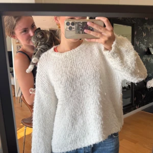 Vit fluffig stickad tröja Pieces - Supermysig vit stickad tröja från Pieces med fluffig känsla och bred ribbad struktur. Tröjan har rund hals och långa ärmar, perfekt för att hålla sig varm. Passar dig som gillar en loose fit och vill ha en enkel men snygg look.